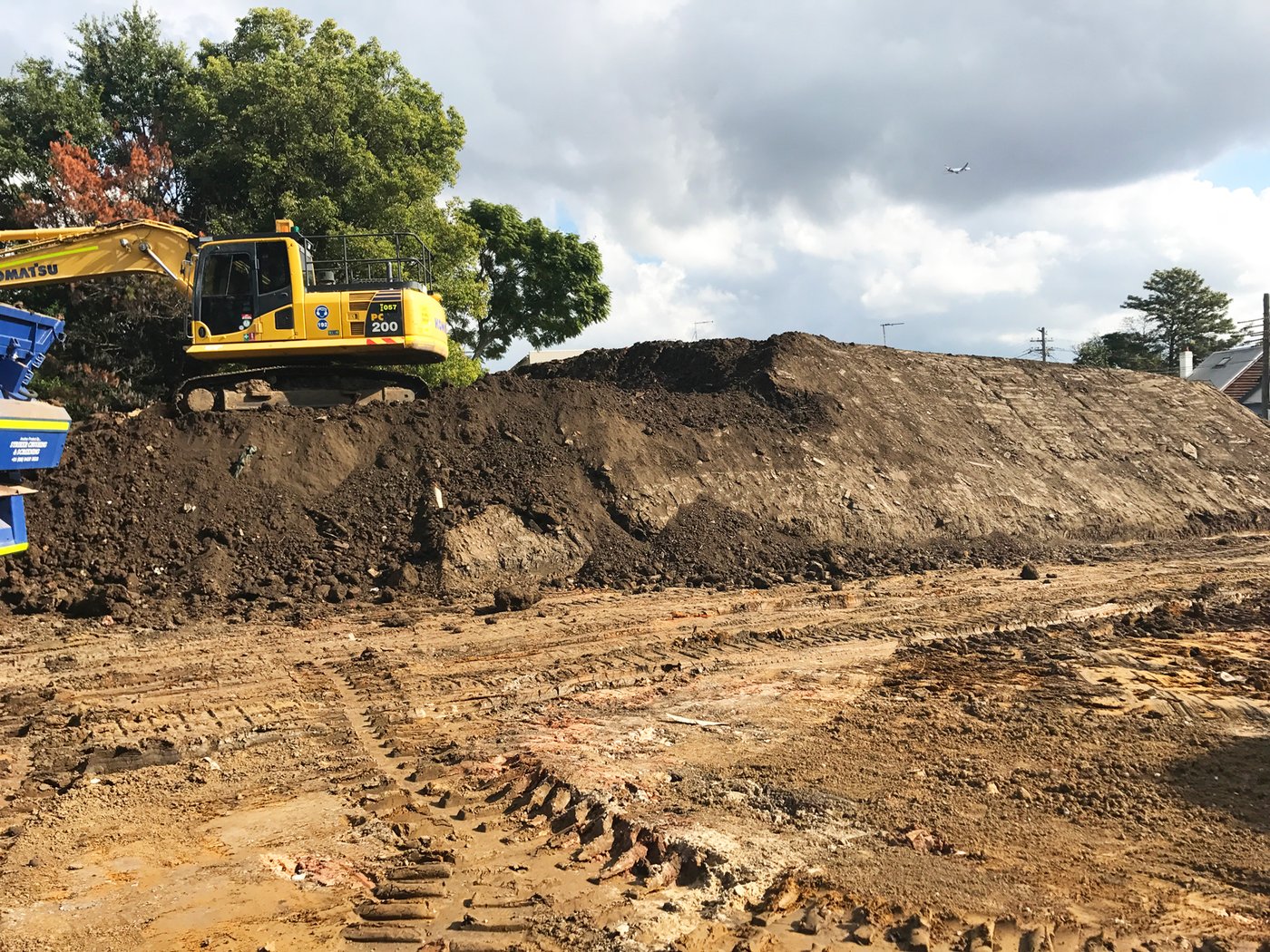 An excavator managing a soil stockpile at a regional site