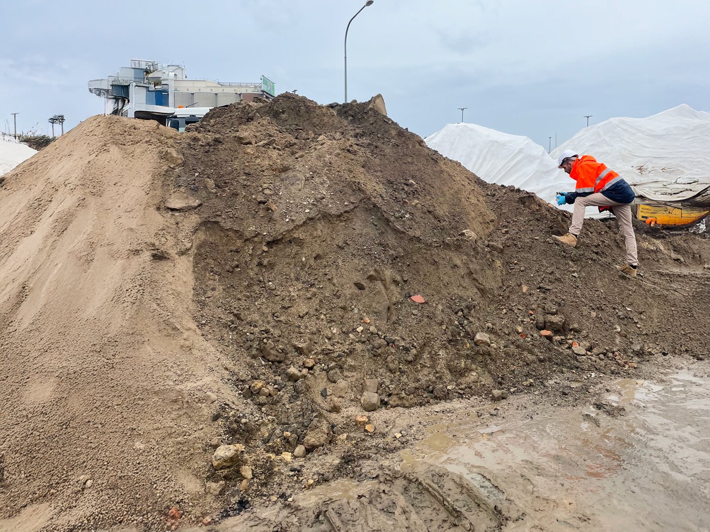 A worker inspecting stockpiled material during contaminated-site works