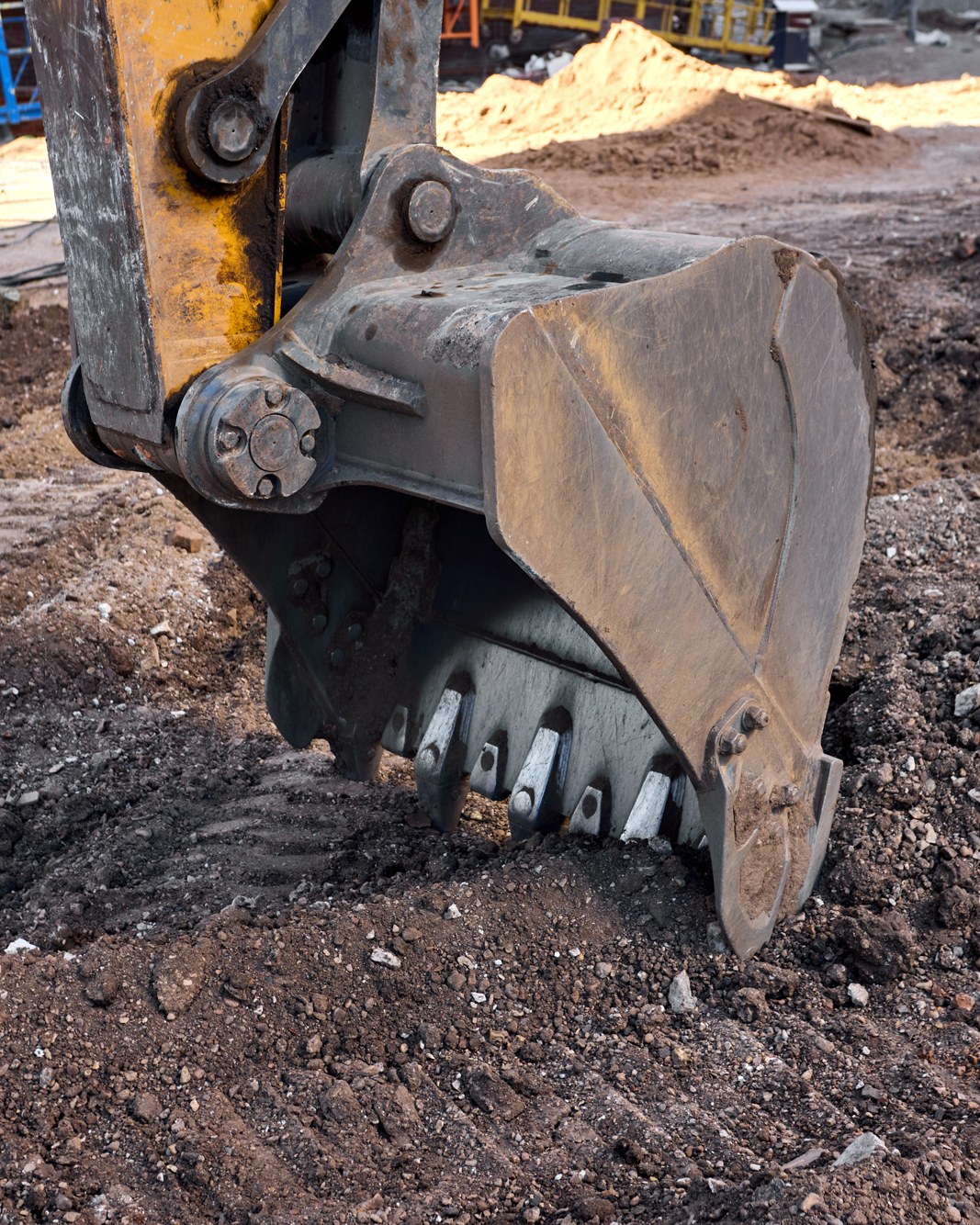 An excavator bucket loading recovered material at a processing site